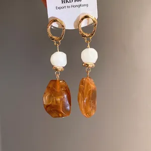 Retro Maillard Harz-Ohrhänger mit goldfarbenen gehämmerten Ringen und weißen Marmorperlen.