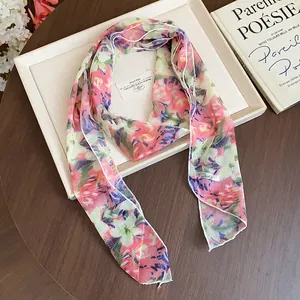 Detailed macro shot of a lightweight floral silk scarf featuring elegant pink and green patterns