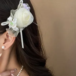 Primo piano di un elegante fermaglio per capelli a rosa in rete crema con perle e nastri