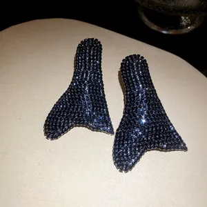 Primo piano di orecchini con pavé di strass neri in un'unica forma di coda di sirena vintage