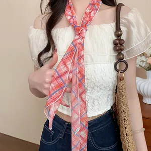 Close-up view of an elegant red plaid skinny scarf worn as a necktie accessory on a lace top