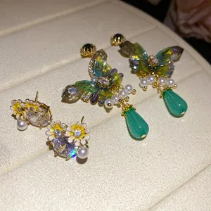 Detailed macro shot of forest style butterfly earrings and zircon flower studs with pearls