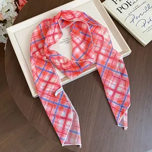 Detail view of a pink and red checkered silk scarf necklace with soft fabric texture