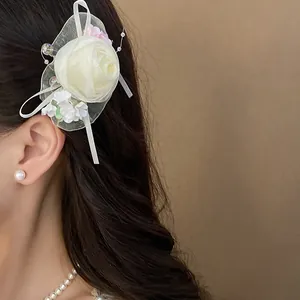 Primo piano di un fermaglio per capelli a rosa in tulle bianco con perline.