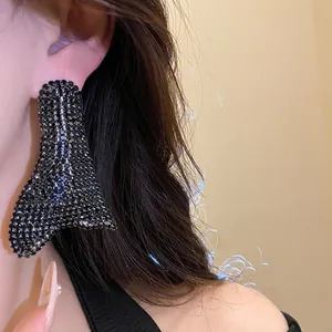 Dettaglio di orecchini geometrici con strass neri sull'orecchio modella