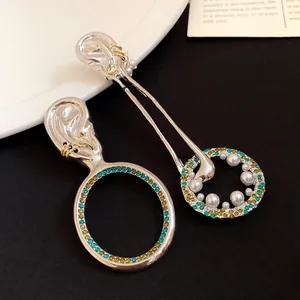 Dettaglio di orecchini vintage asimmetrici a forma di orecchio con strass colorati