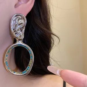 Primo piano di orecchini a cerchio vintage esagerati a forma di orecchio con strass colorati