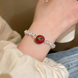 Close-up of a sweet beaded bracelet featuring a red resin apple pendant on wrist