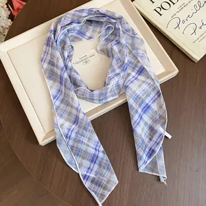 Close-up of elegant purple and blue plaid scarf on a beige display tray.