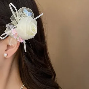 Dettaglio di un'elegante clip per capelli a rosa in rete bianca con perline sui capelli.