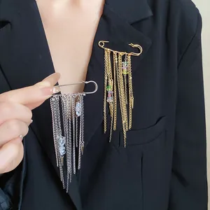 Detail view of tassel chain safety pin brooch with stones worn on a black blazer.