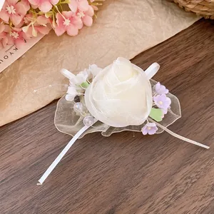 Dettaglio di un fermaglio per capelli a rosa in tulle bianco crema con perle e nastri