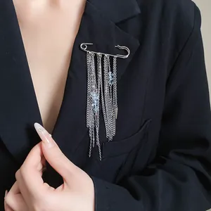 Close-up of vintage silver safety pin brooch with long chain tassels and stones