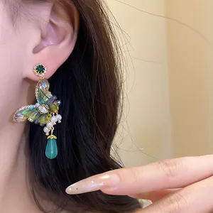 Detailed macro view of elegant butterfly dangle earring with pearls and green gemstone