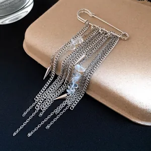 Macro detail of safety pin brooch with silver chain tassels and clear stones
