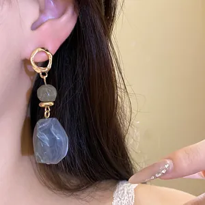 Nahaufnahme von eleganten, blau-grauen, unregelmäßigen Harz-Ohrringen mit goldenem Vintage-Finish