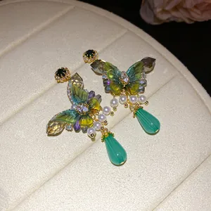 Close-up view of elegant butterfly earrings featuring zircon crystals and pearl accents.