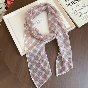 Elegant plaid silk scarf neck accessory displayed on a cream tray and wooden table.