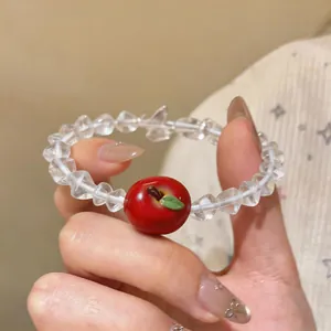 Close-up detail of a sweet beaded bracelet featuring a charming red resin apple pendant