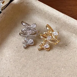 Elegant 18k gold plated zircon bowknot ear cuffs in gold and silver finishes on tray.