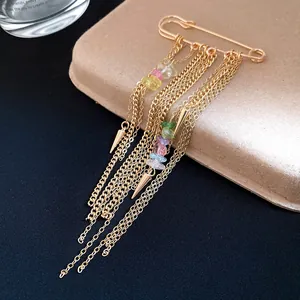 Close-up detail of retro gold chain tassel brooch with colorful crushed stones and metal pendants.