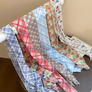 Macro detail of various plaid and floral patterned chiffon silk scarves draped neatly.