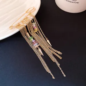 Close-up of vintage gold chain tassel brooch with multicolored stones on safety pin