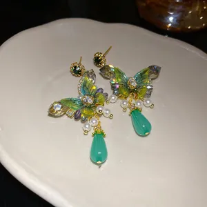 Detailed macro shot of vintage butterfly earrings featuring green pearls and crystal accents