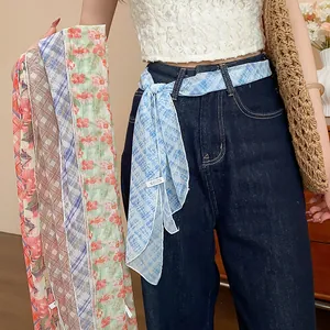 Detail view of floral and checkered silk scarves styled as a fashionable waist belt