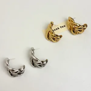 Detailed close-up of C-shaped chunky twisted chain stud earrings in gold and silver finish