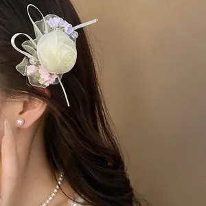 Primo piano di un fermaglio per capelli con rosa in rete avorio su capelli scuri