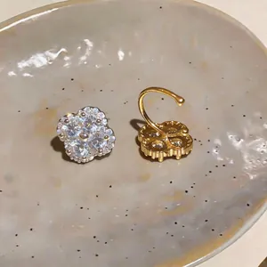 Detailed close-up of a sparkling 18k gold plated flower ear cuff with pavé zircons.