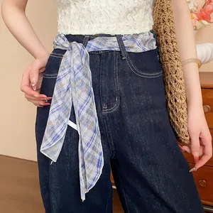 Detail view of a blue and white plaid silk scarf styled as a fashion belt on denim jeans