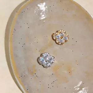 Close-up detail of gold and silver zircon flower ear clips for non-pierced ears on a plate.