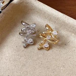 Macro detail of 18k real gold plated bow-shaped ear cuffs with sparkling pear-cut zircons