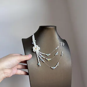 Detailed view of a multi-layer white beaded necklace with handmade flower and tassels.