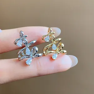 Detail view of gold and silver bow ear cuffs set with sparkling pear-cut zircons