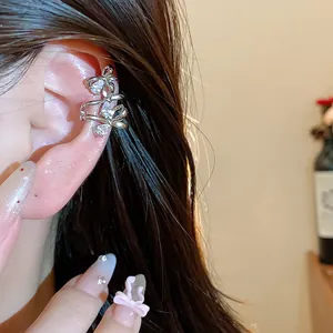 Close-up of elegant 18k gold plated zircon bow ear cuff worn on ear detail.