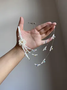 Detailed view of a multi-layer beaded necklace with white woven flower and iridescent beads.