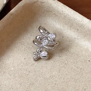 Exquisite macro detail of silver-toned triple bow ear cuff with sparkling pear-cut zircon stones