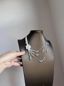Detailed view of white beaded multi-layer necklace with flower and tassel accents