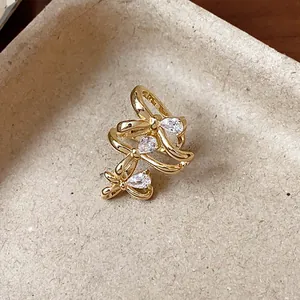Macro detail of 18k gold plated triple bow ear cuff with sparkling pear-cut zirconias.