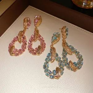 Exquisite feather drop earrings featuring pink and blue crystals with a golden finish