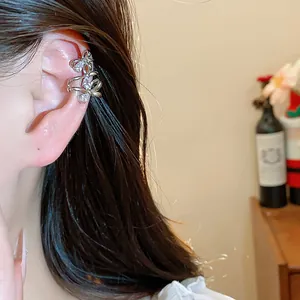 Elegant close-up of an 18k gold-plated zircon bow ear cuff worn on a model's ear.