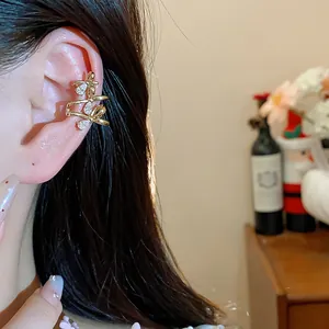 Close-up of an 18k gold-plated bow ear cuff with zircons elegantly worn on an ear