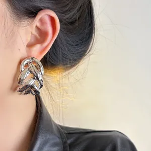 Detail view of chunky silver braided chain earrings with a high-shine metallic finish.
