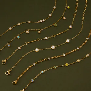 Detailopname van vergulde roestvrijstalen armbanden met gekleurde zirkoniasteentjes.