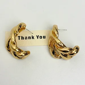 Detail view of chunky gold-tone C-shaped twisted chain earrings with silver needles