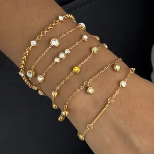 Gedetailleerde weergave van gouden roestvrijstalen armbanden met zirkonia aan de pols.