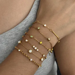 Stapelbare gouden roestvrijstalen armbanden met gekleurde zirkonia aan de pols